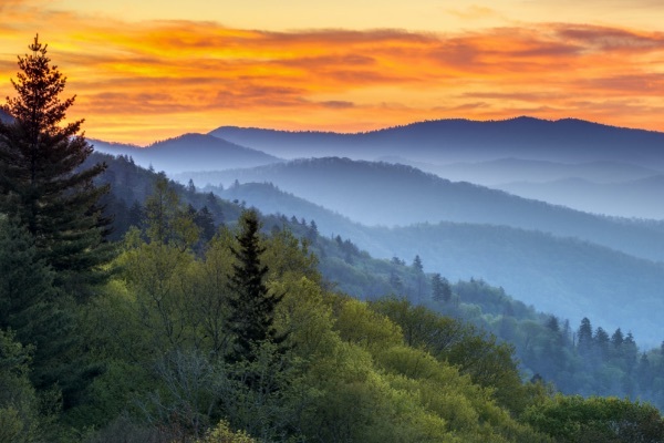 a gorgeous orange sunset sets behind blue mountains in the Great Smoky Mountains National Park
