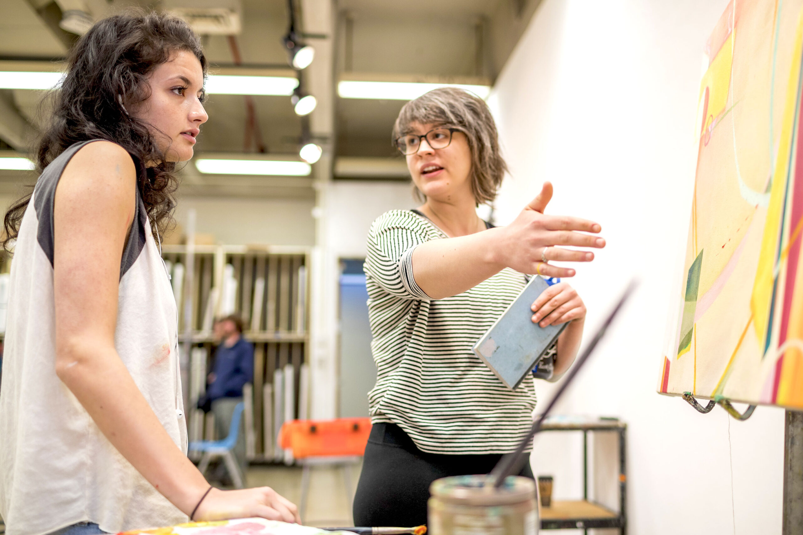 A student receives helpful instruction from supporting faculty in the painting studio during an art class
