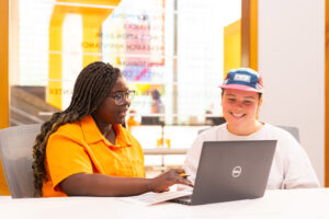 Two students work off a laptop