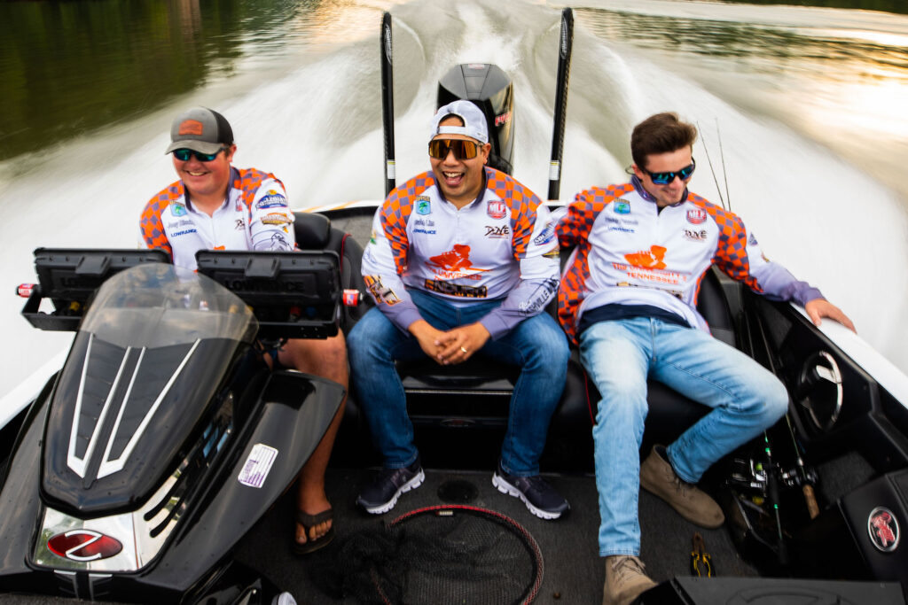 Three students ride in the back of a speedboat after a day of bass fishing