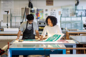 Students look over recently screen printed artwork on a light table